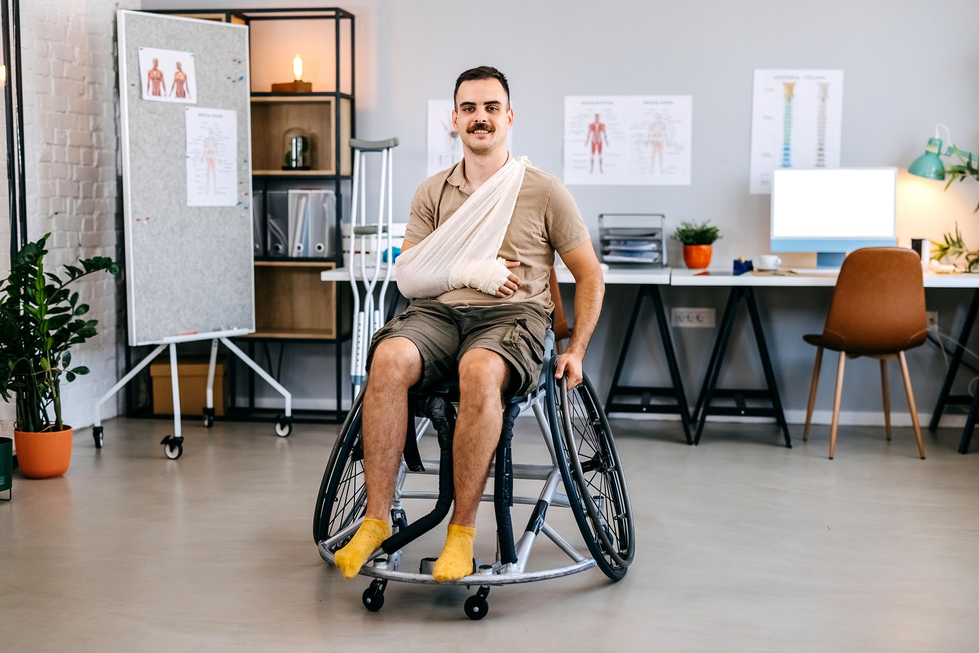 Man sits in a wheelchair with a broken arm