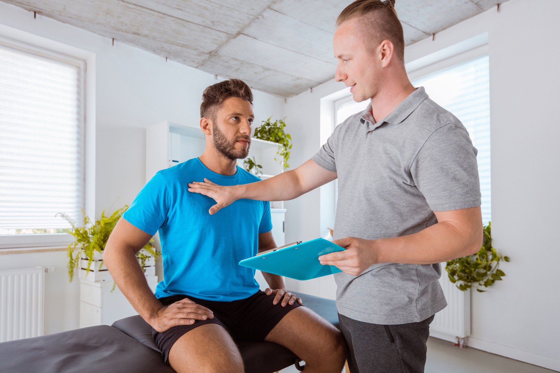 Physical therapist examining young man in rehabilitation center